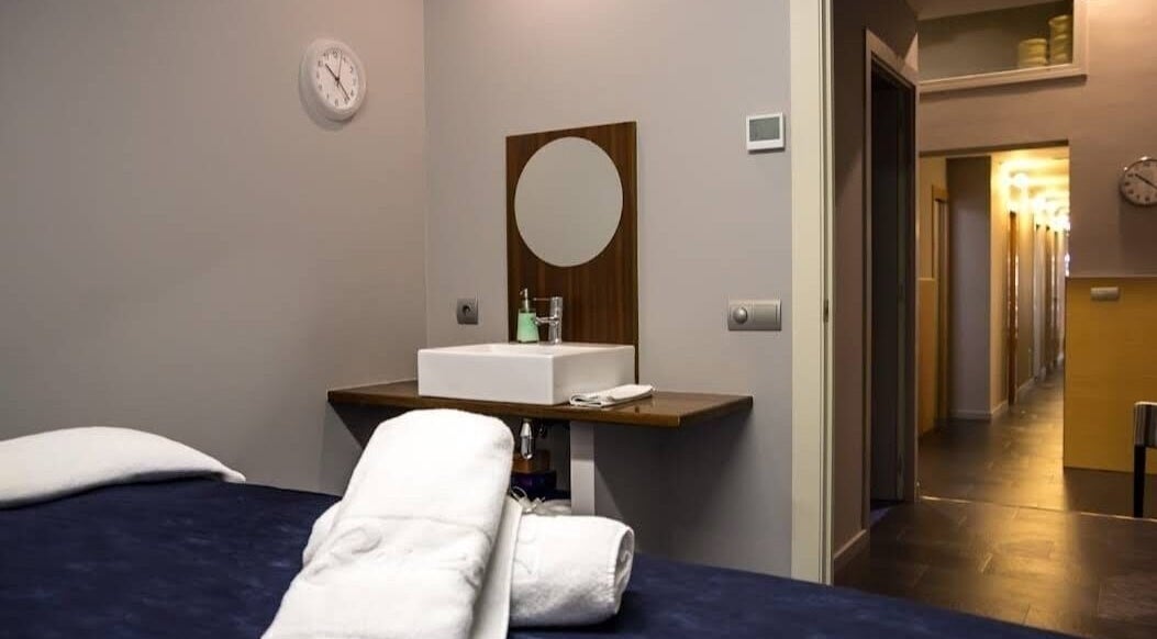 Habitación de masajes en Benessia & Benestar, Barcelona, Catalunya, ES, con cama y lavabo moderno.