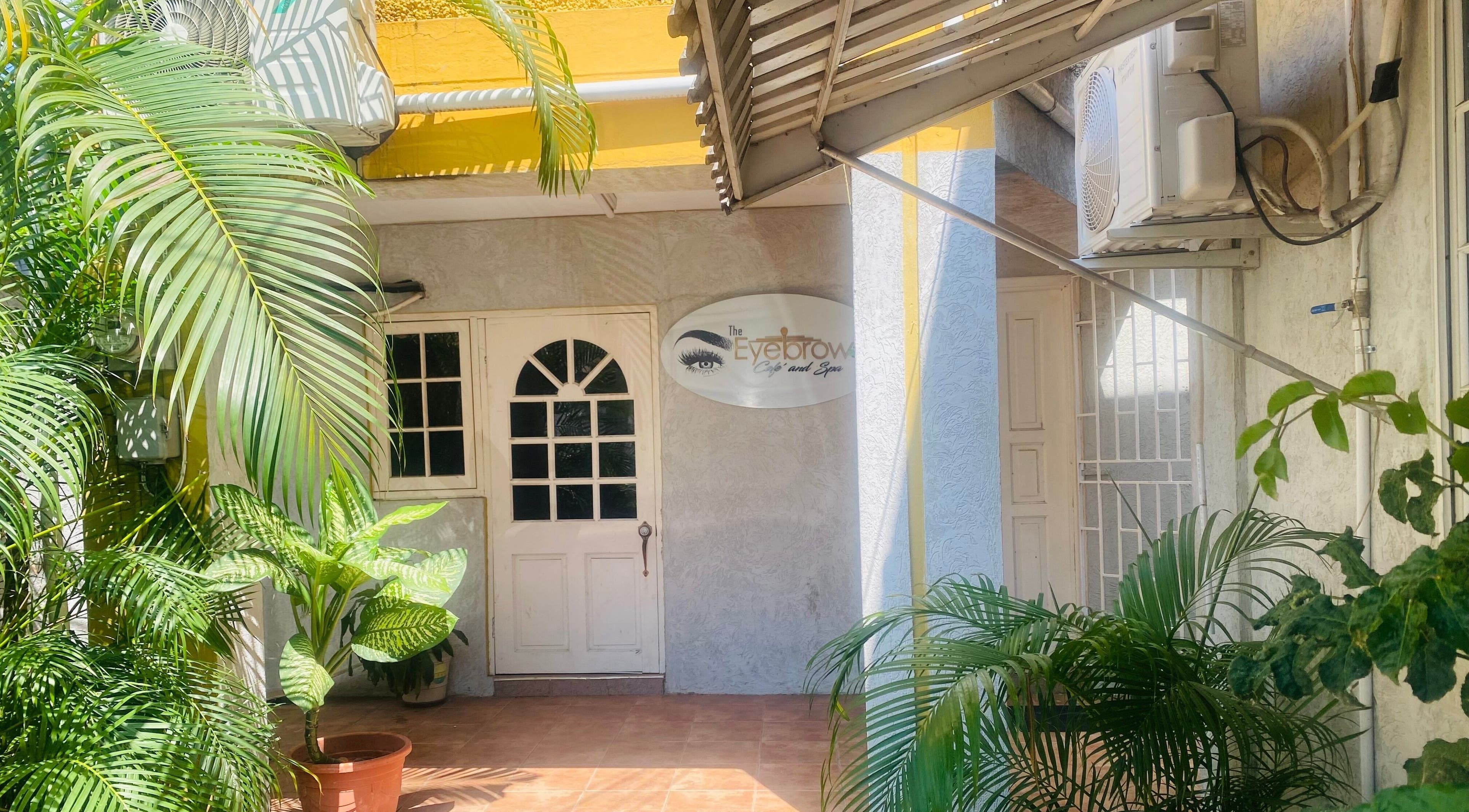 Entrance to Healing Emerald Wellness Spa & Training Centre Ltd, Kingston, St. Andrew Parish, with lush greenery.