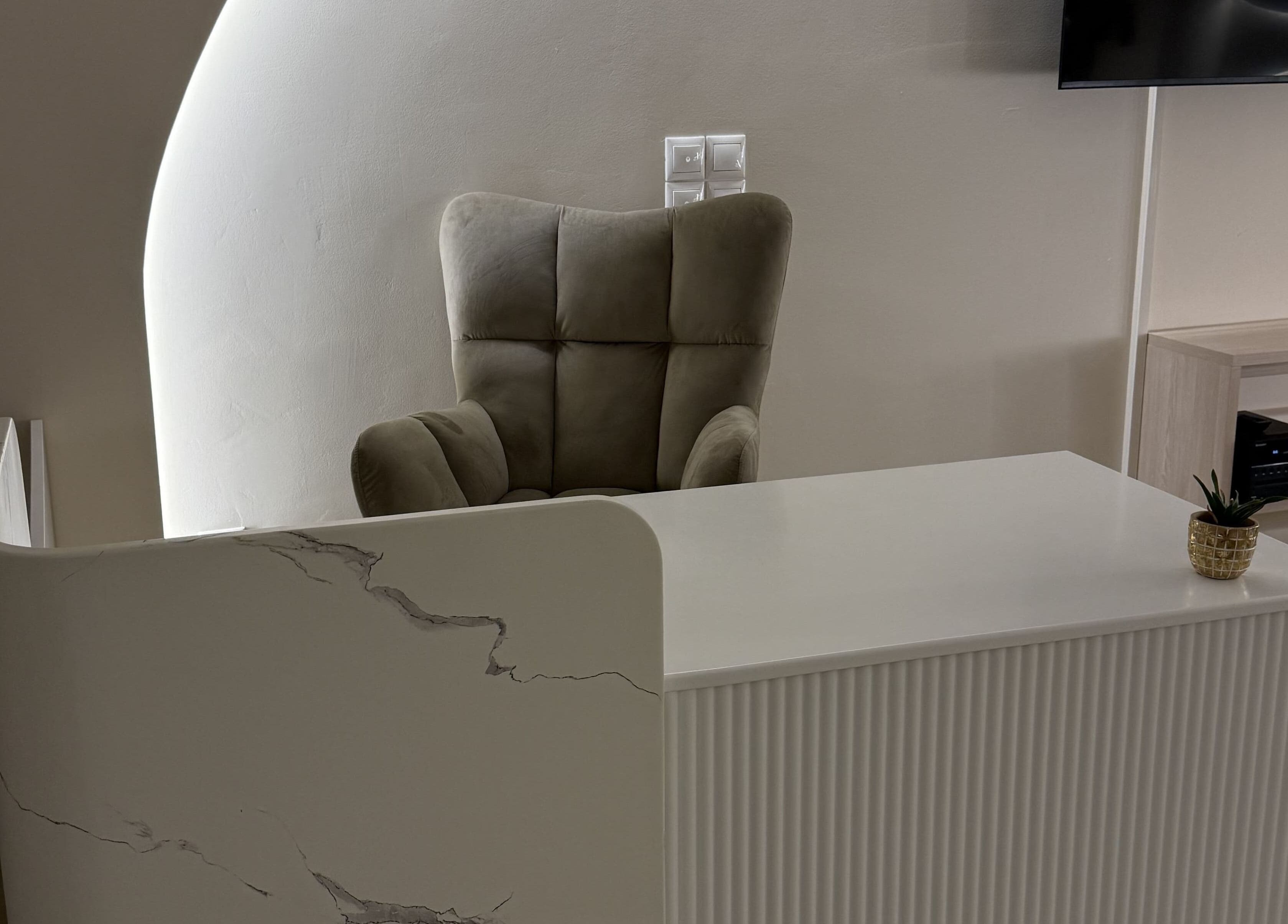 Κομψή υποδοχή στο Feel Queen, Γέρακας, GR με πολυθρόνα πίσω από λευκό γραφείο.