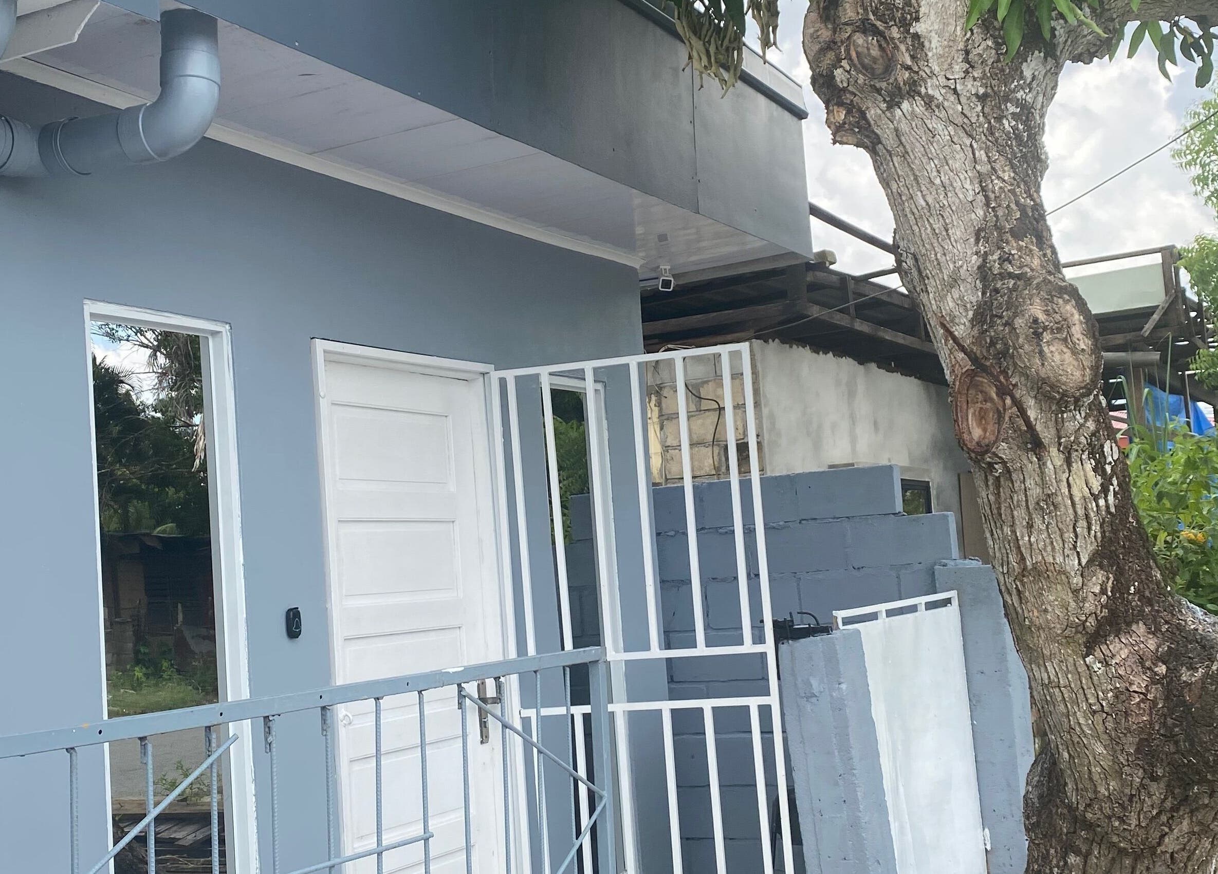 Exterior view of Sparkle Waxing Bar & More, Paramaribo, SR with tree and blue-gray building facade.