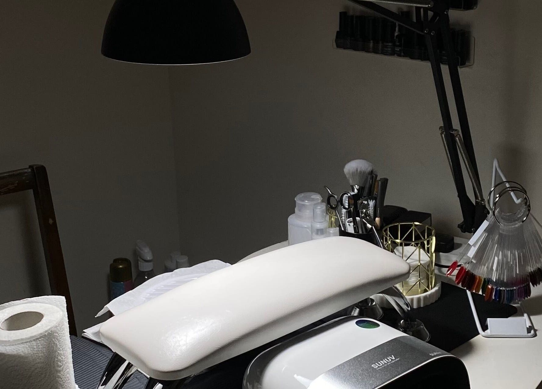 Nail setup at Mayasnailstudiox in Llay, Wales, GB with tools and UV lamp on a manicure table.