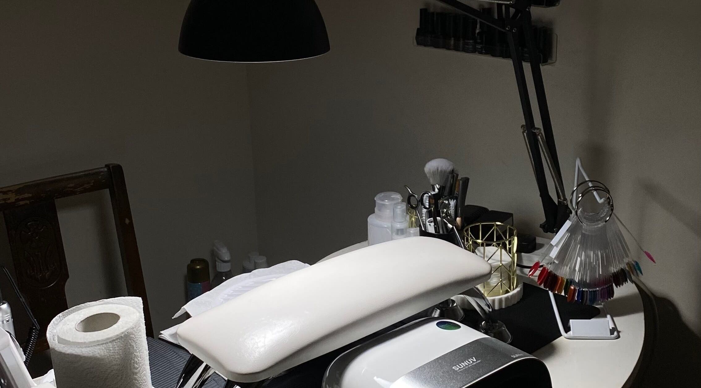 Nail setup at Mayasnailstudiox in Llay, Wales, GB with tools and UV lamp on a manicure table.