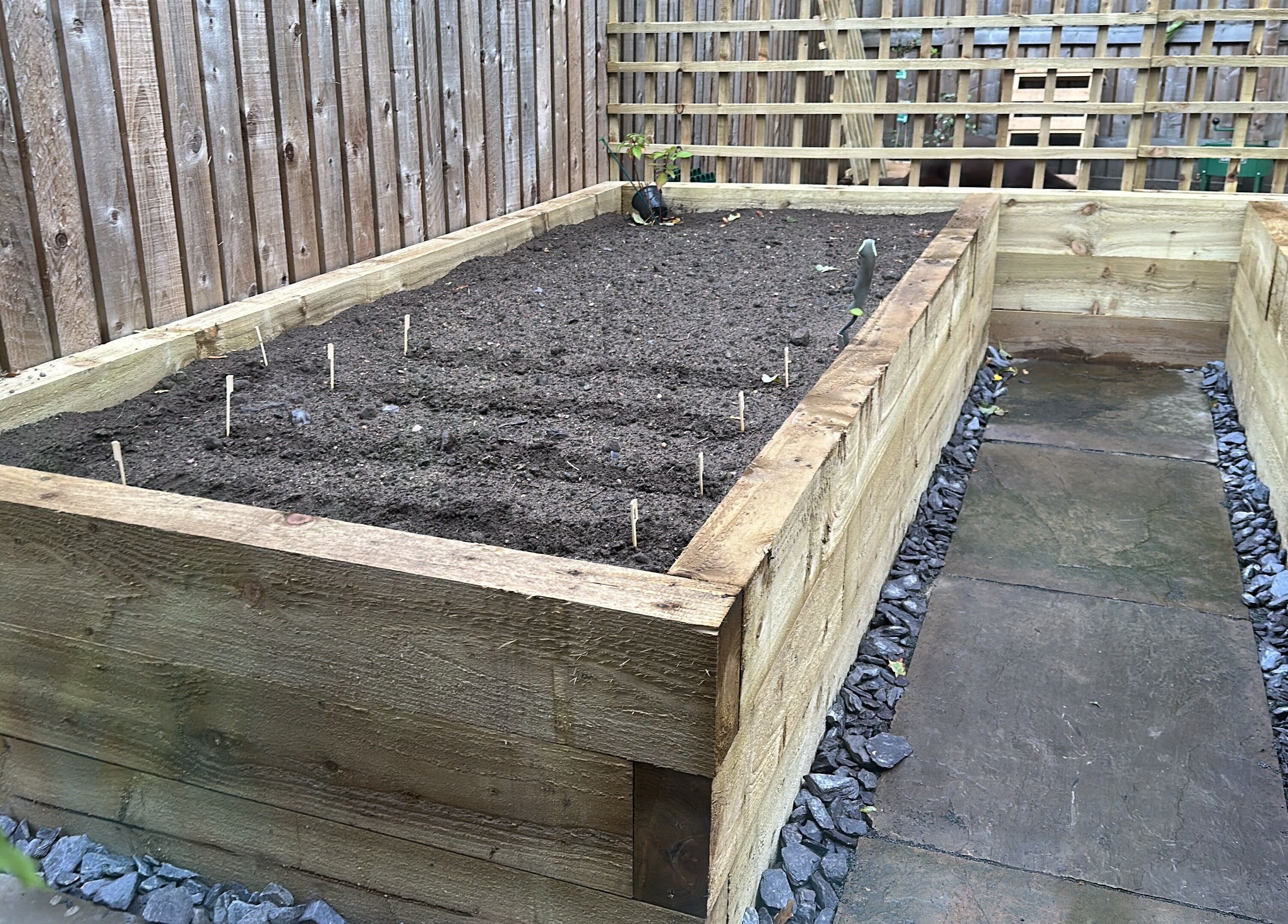 Wooden garden bed and stone path at Kate’s massage, Castleford, England, GB, creating a tranquil outdoor spot.