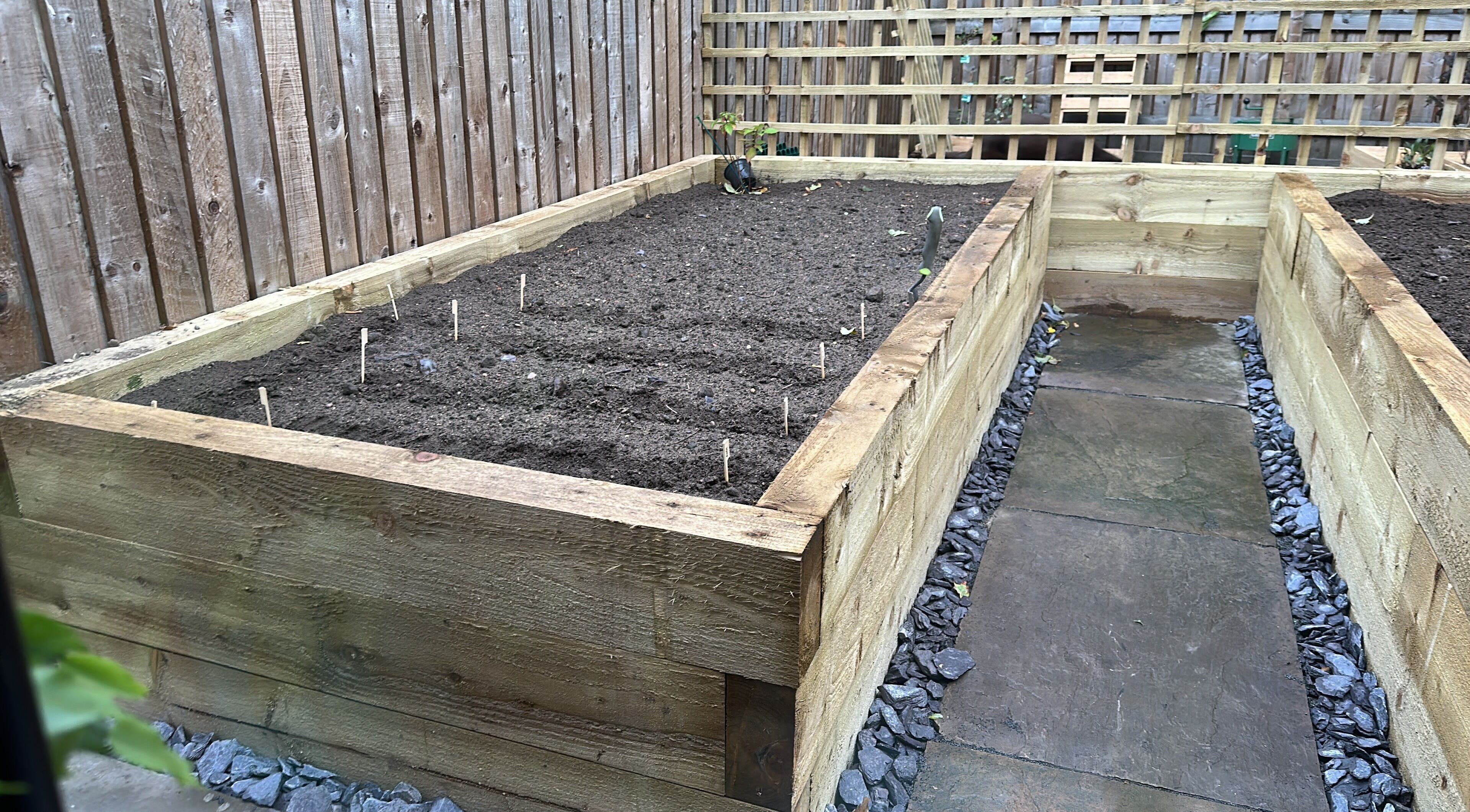 Wooden garden bed and stone path at Kate’s massage, Castleford, England, GB, creating a tranquil outdoor spot.