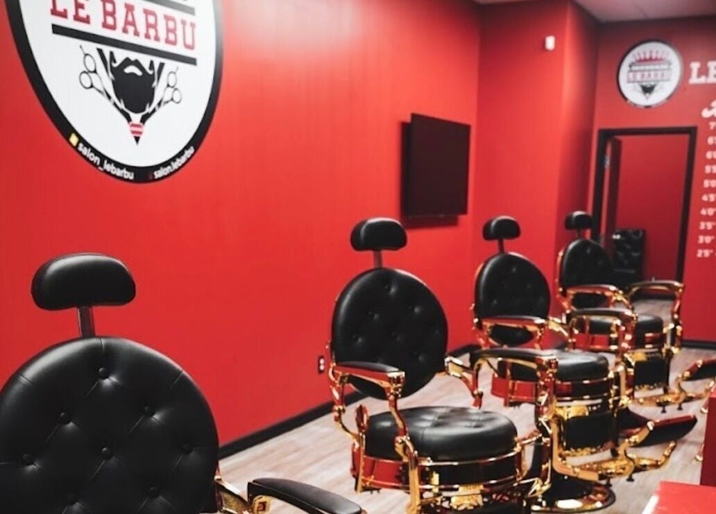 Barber chairs in Le Barbu Henri-Bourassa salon, Montréal, Québec, CA with red walls and elegant decor.