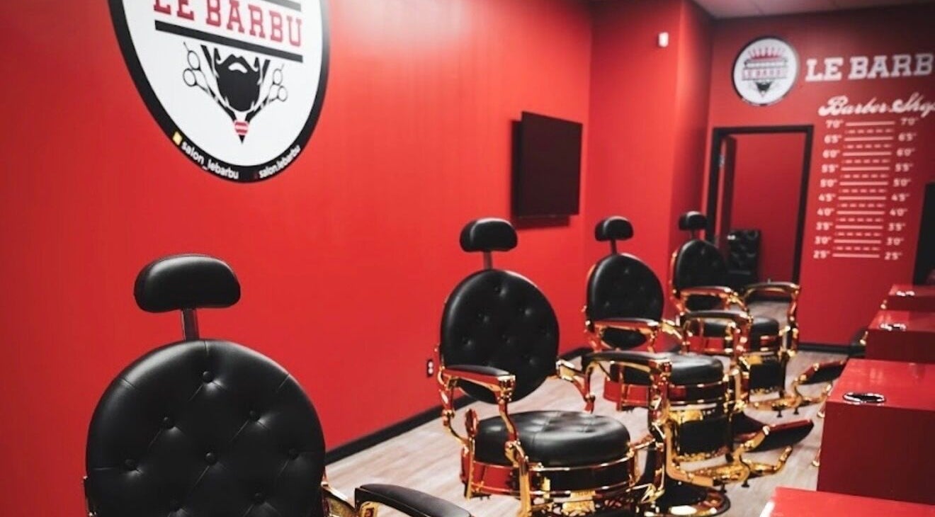 Barber chairs in Le Barbu Henri-Bourassa salon, Montréal, Québec, CA with red walls and elegant decor.