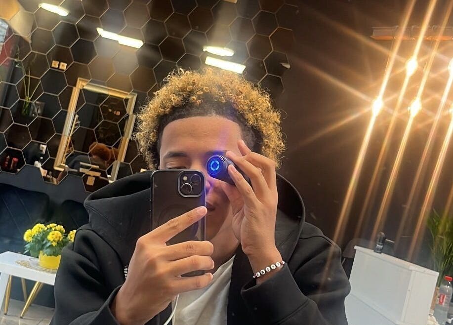 Client at Tstar.The.Barber, Dudelange, with chic interior and glowing lights.