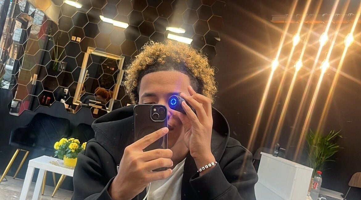 Client at Tstar.The.Barber, Dudelange, with chic interior and glowing lights.