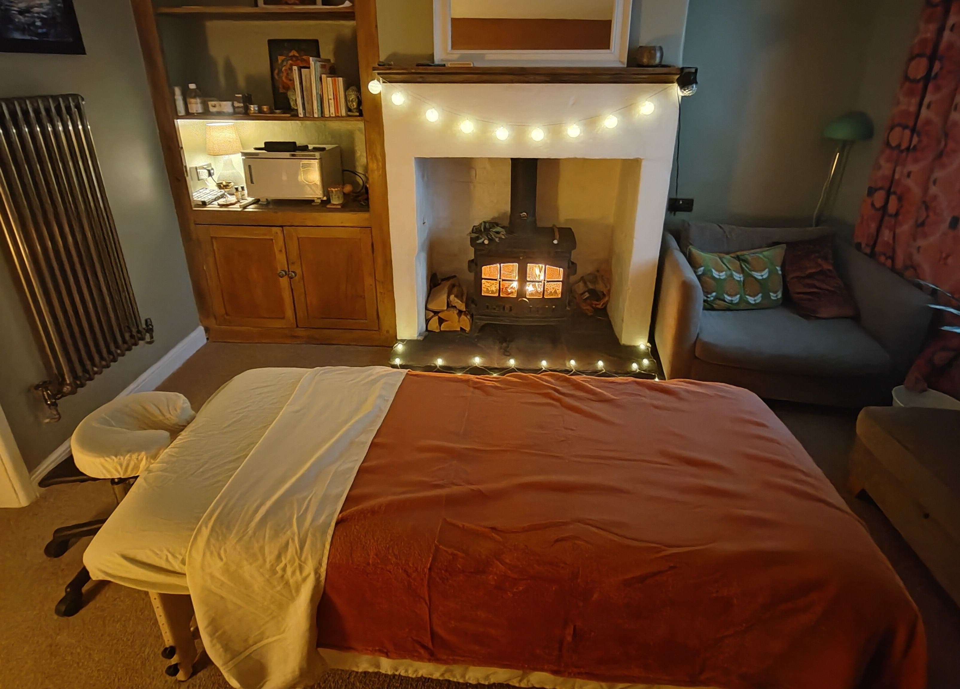 Tranquil massage room at Metta Massage Therapies, Galgate, England, GB with a warm fireplace and soothing ambiance.