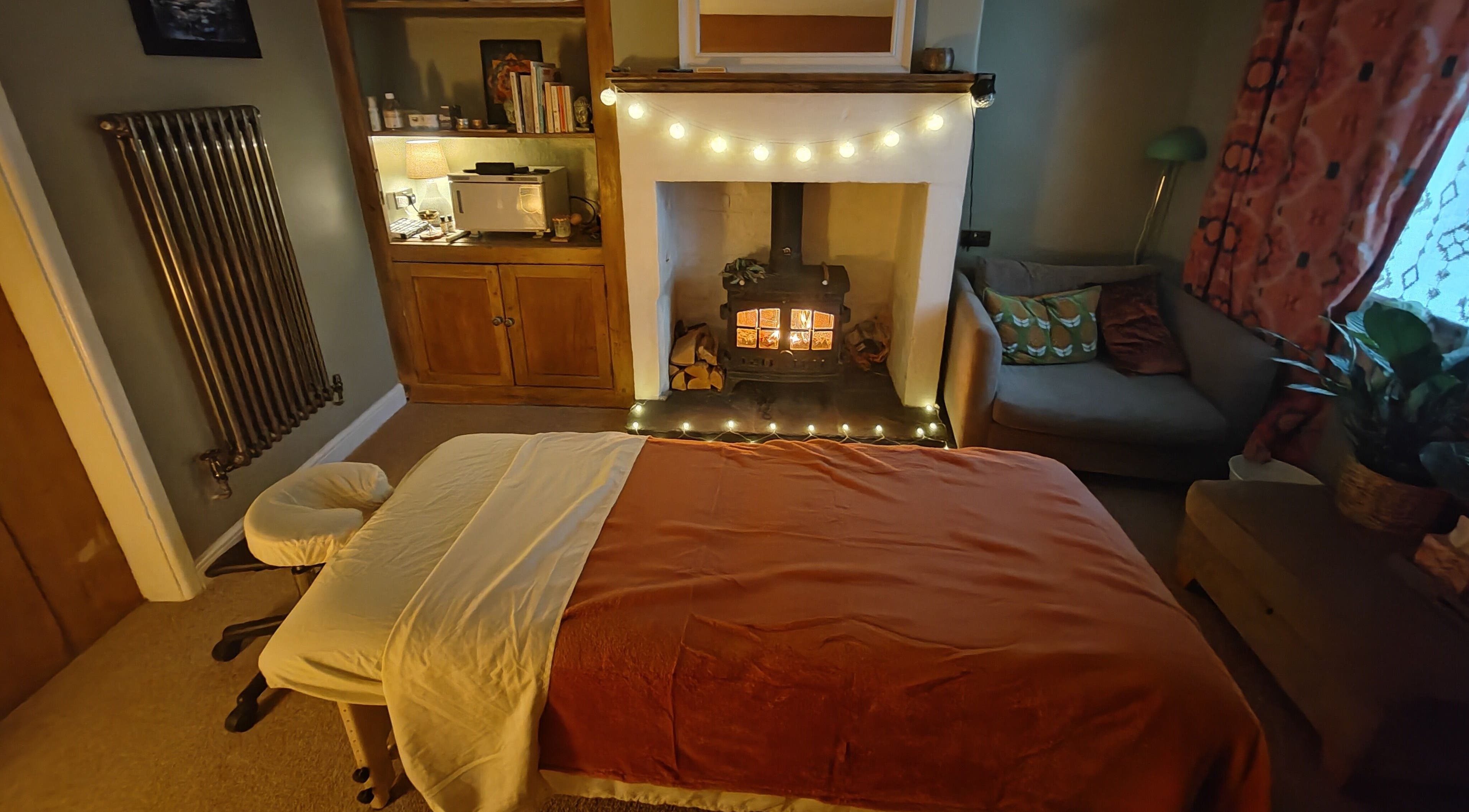 Tranquil massage room at Metta Massage Therapies, Galgate, England, GB with a warm fireplace and soothing ambiance.