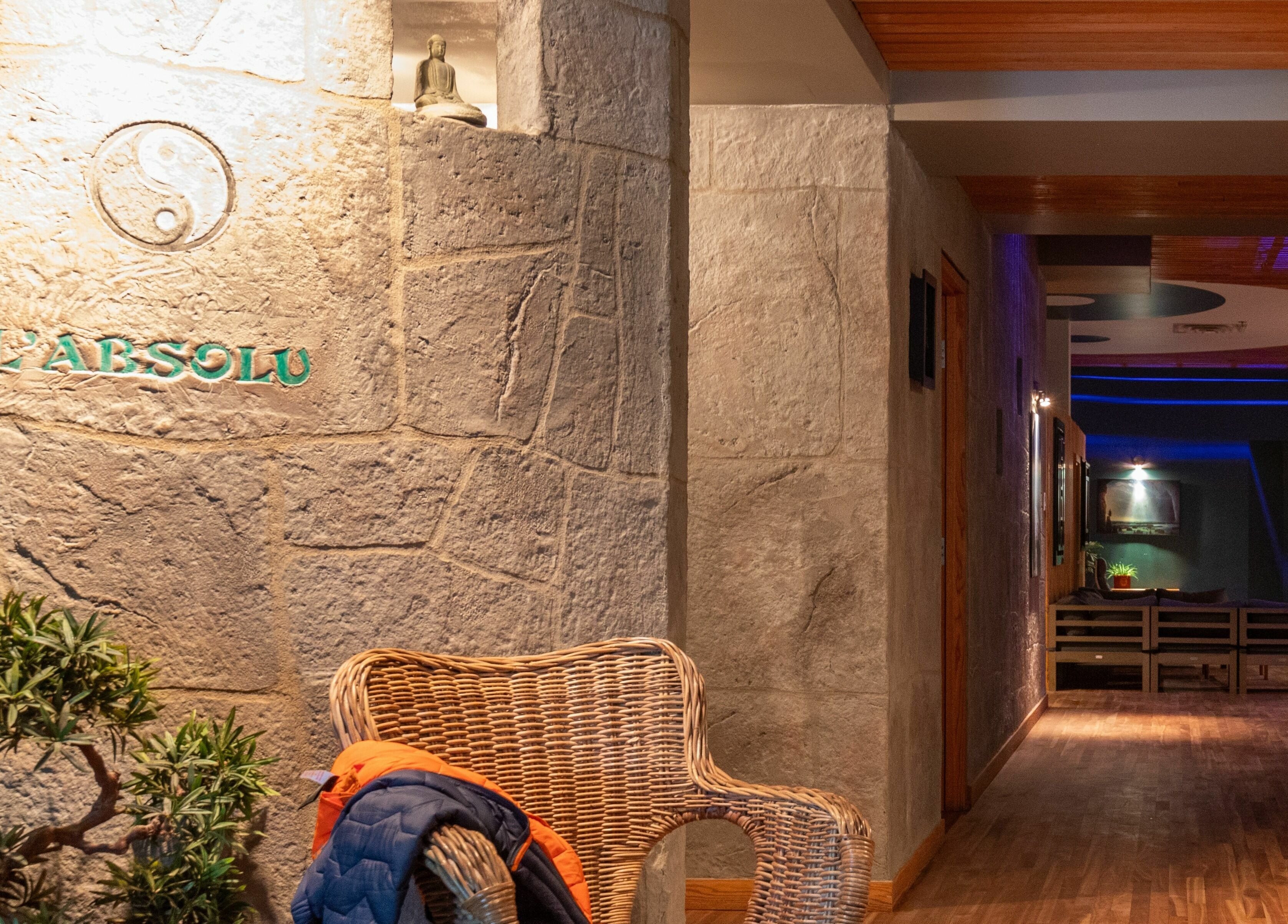 Entrée chaleureuse de L'Absolu Spa à Montréal, Québec, CA, avec mur en pierre et chaise en osier.