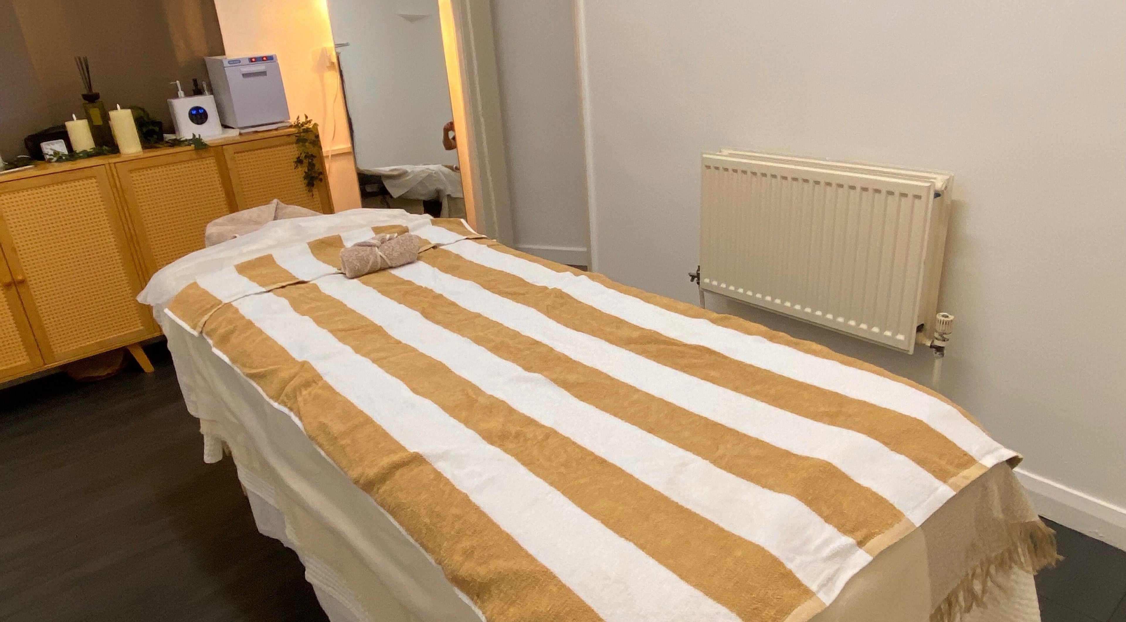 Tranquil massage room at Asiana Massage Studio, Salford, England, GB, featuring a cozy striped massage table.