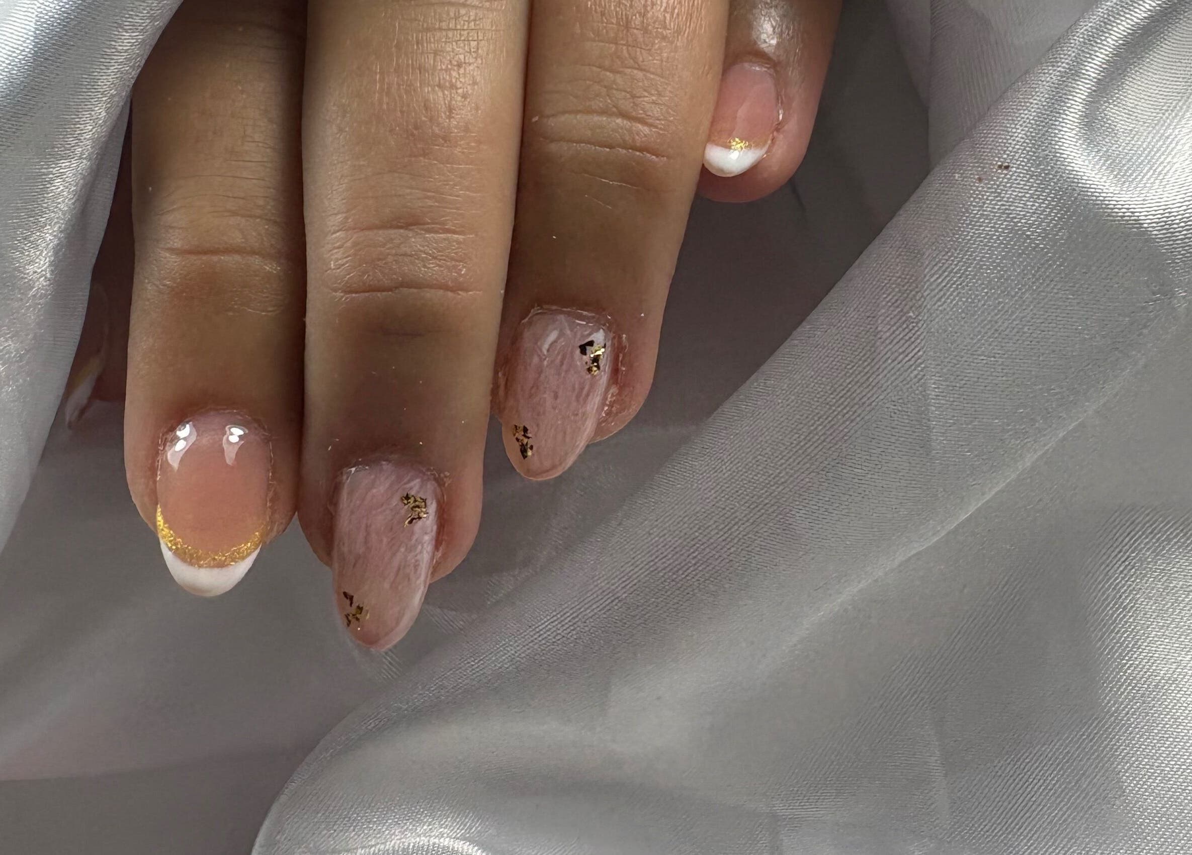 Elegant gold-accent nail art by Nails By Carolina in PT on silky white fabric.