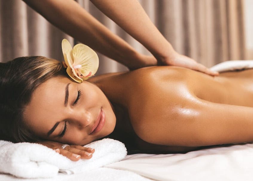Woman enjoying soothing massage at Mayra Gama, Houston, Texas, US with an orchid flower in her hair.
