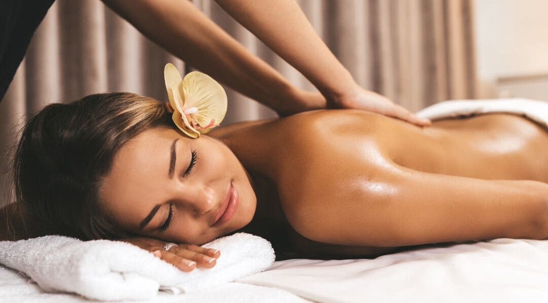 Woman enjoying soothing massage at Mayra Gama, Houston, Texas, US with an orchid flower in her hair.