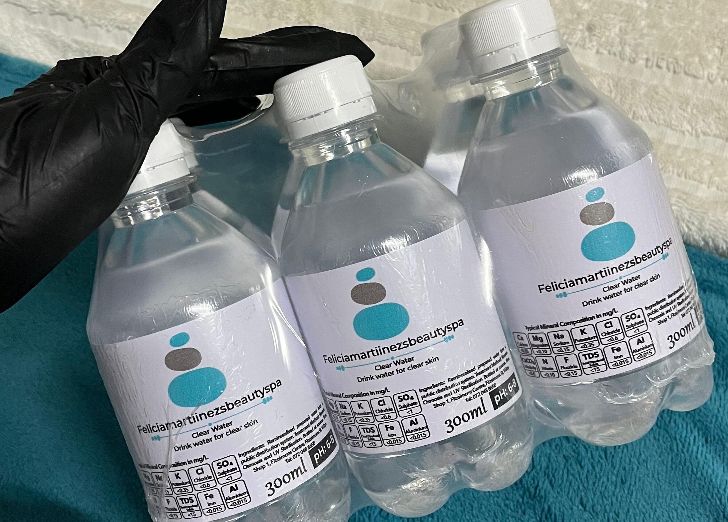 Bottled water branded with Felicia.ciamartiinezsbeautyspa, Vanderbijlpark, Gauteng, ZA, on teal backdrop.