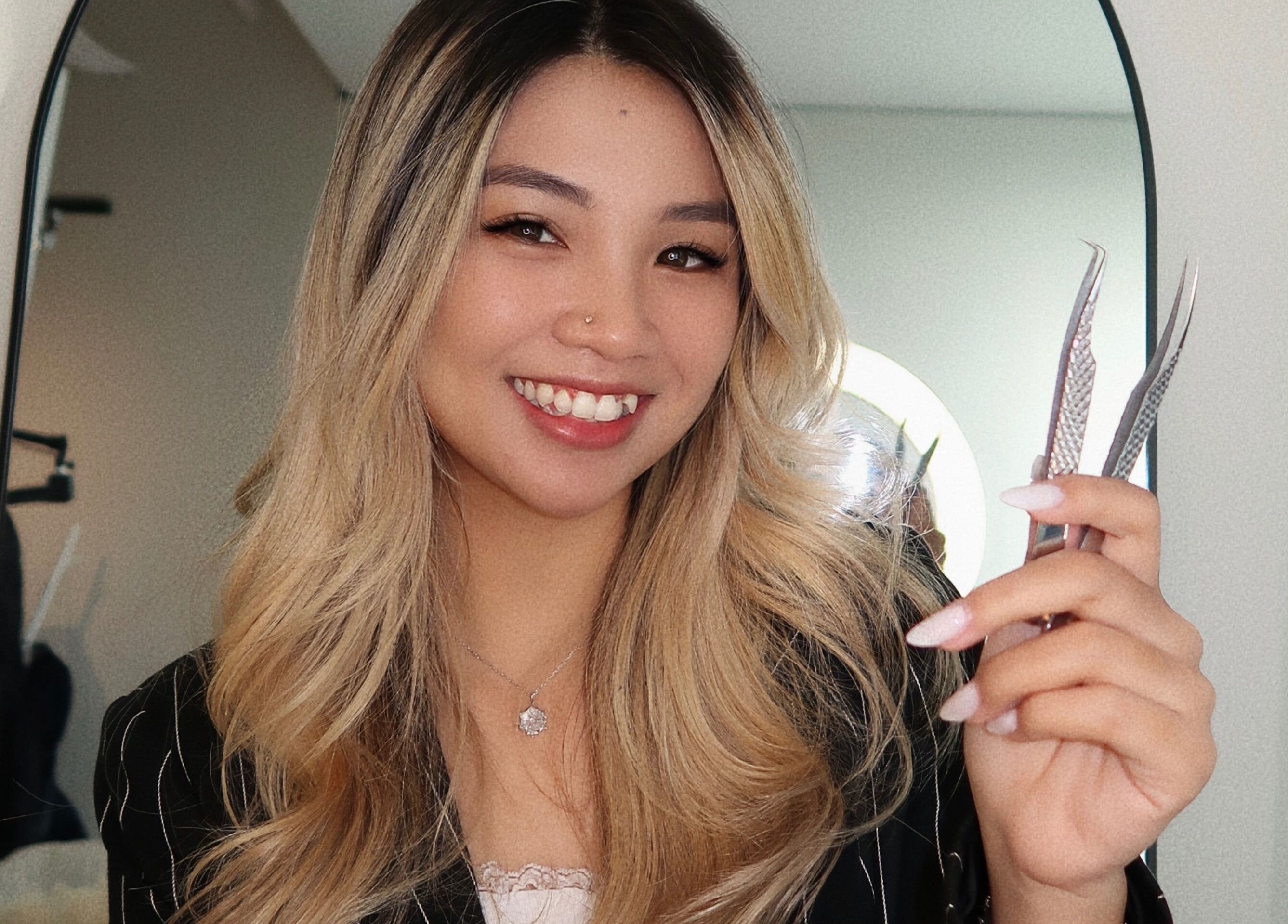 Smiling stylist holding lash tools at LASHBYRACHEL in Burnaby, British Columbia, CA.