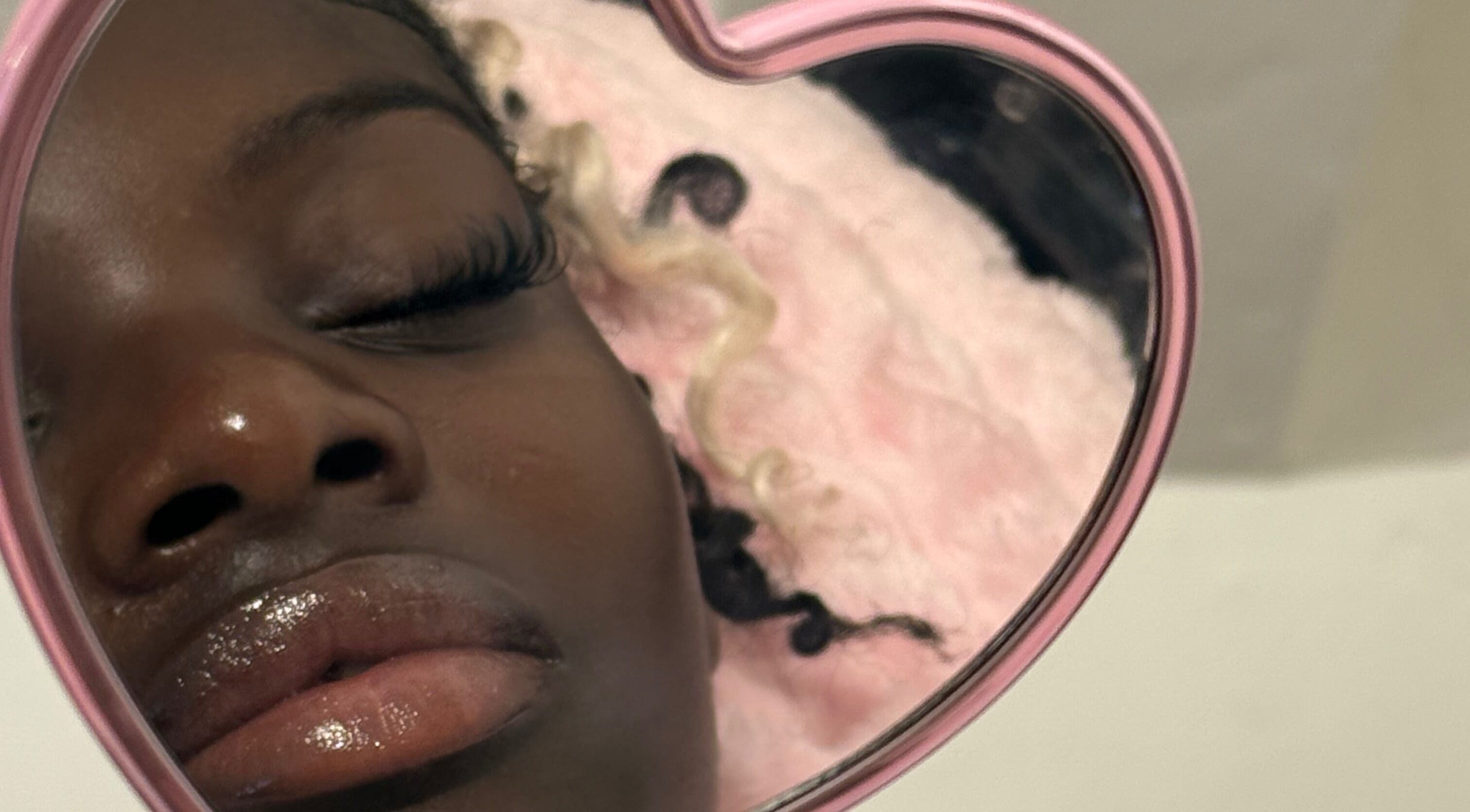 Close-up of a woman's reflection in a heart-shaped mirror at Lashed By Daé, Cape Town, Western Cape, ZA.