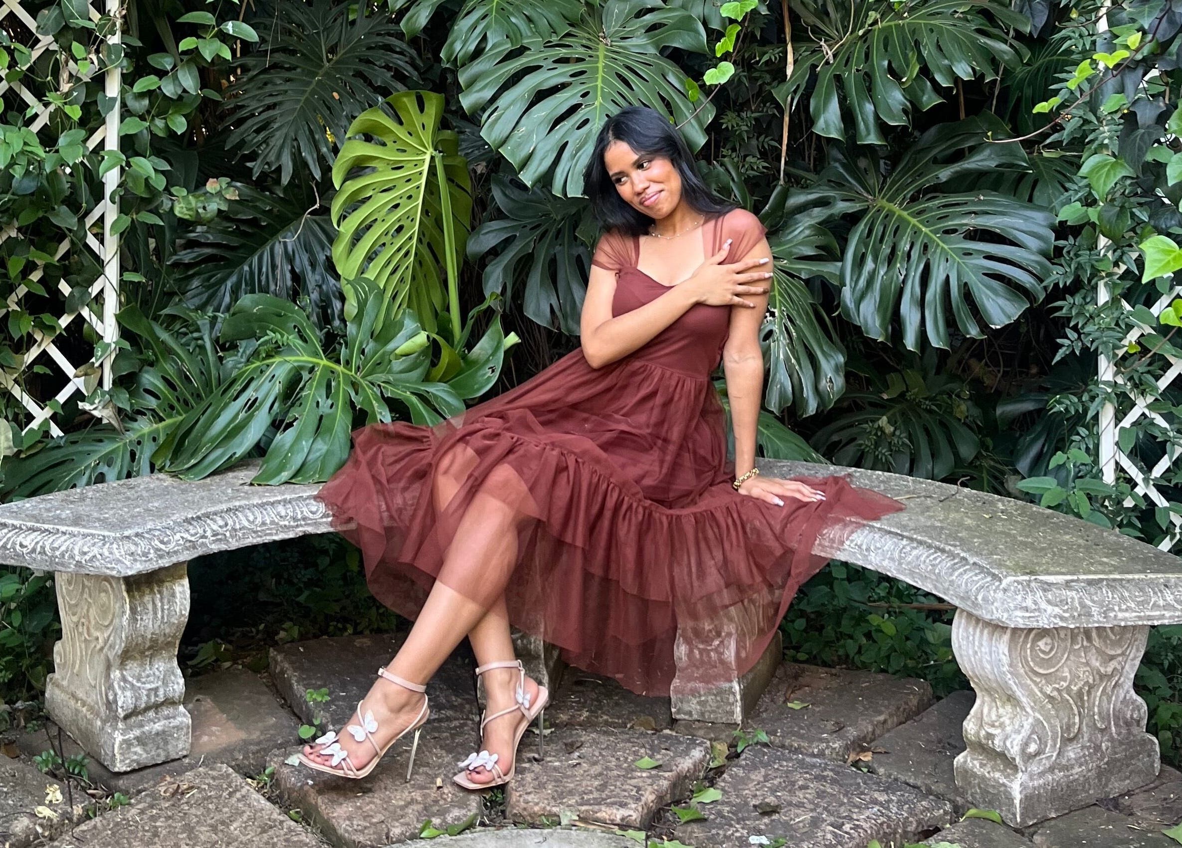Serene garden scene at Lashed By Daé, Cape Town, Western Cape, ZA with elegant woman on stone bench.