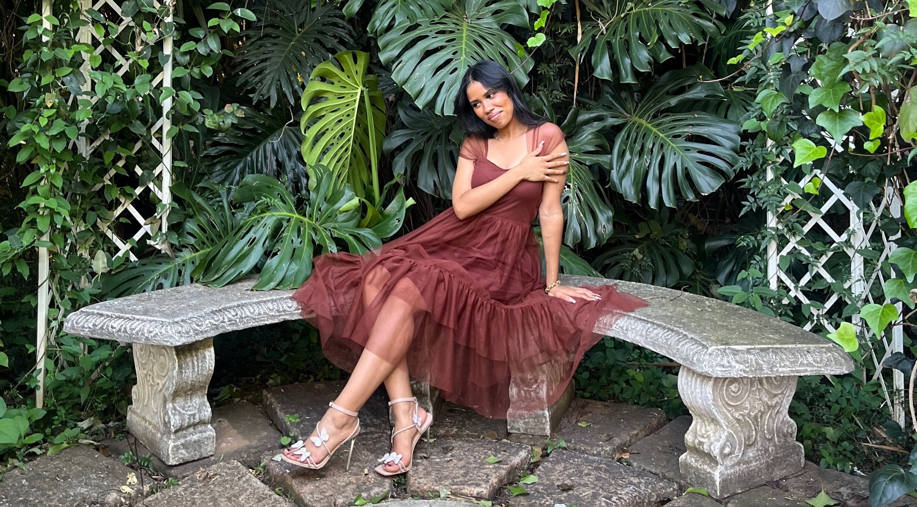 Serene garden scene at Lashed By Daé, Cape Town, Western Cape, ZA with elegant woman on stone bench.