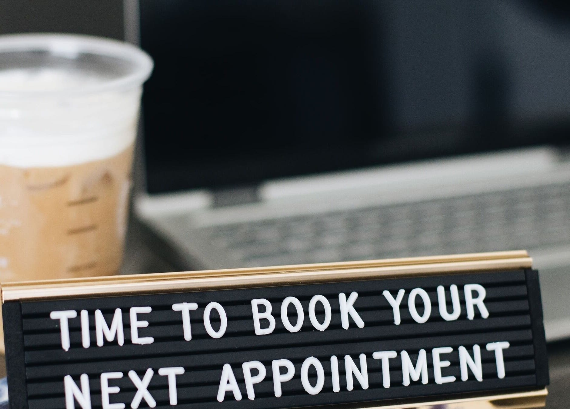 KF Hair Beauty Lifestyle in Fleetwood, England, GB encourages bookings with a laptop and coffee beside a sign.
