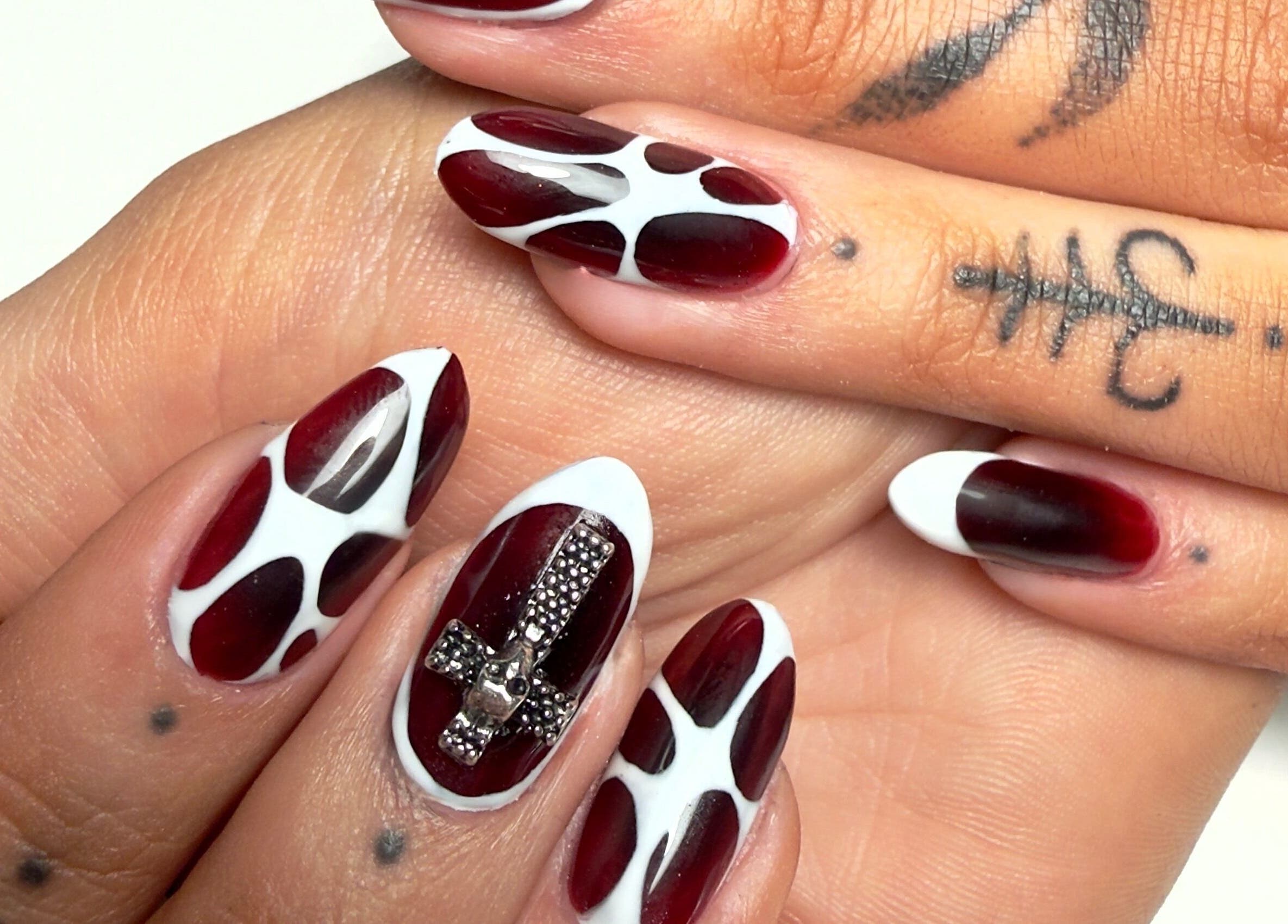 Intricate red and white nail design at Laurs Claws, Bedford, England, GB, showcasing unique nail artistry.