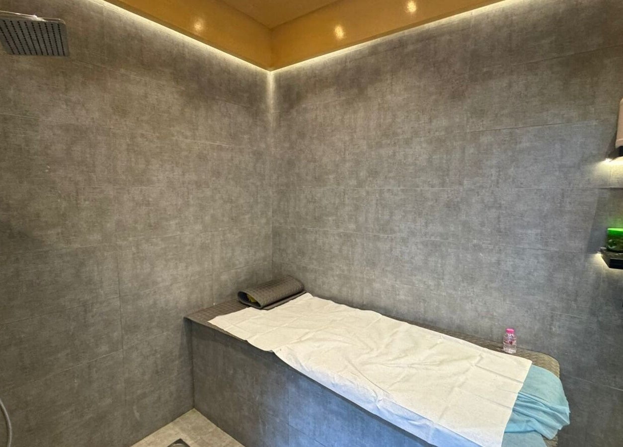 Modern wellness room at Three Brothers Barbershop, Sharjah, AE, featuring a sleek shower and spa bed.