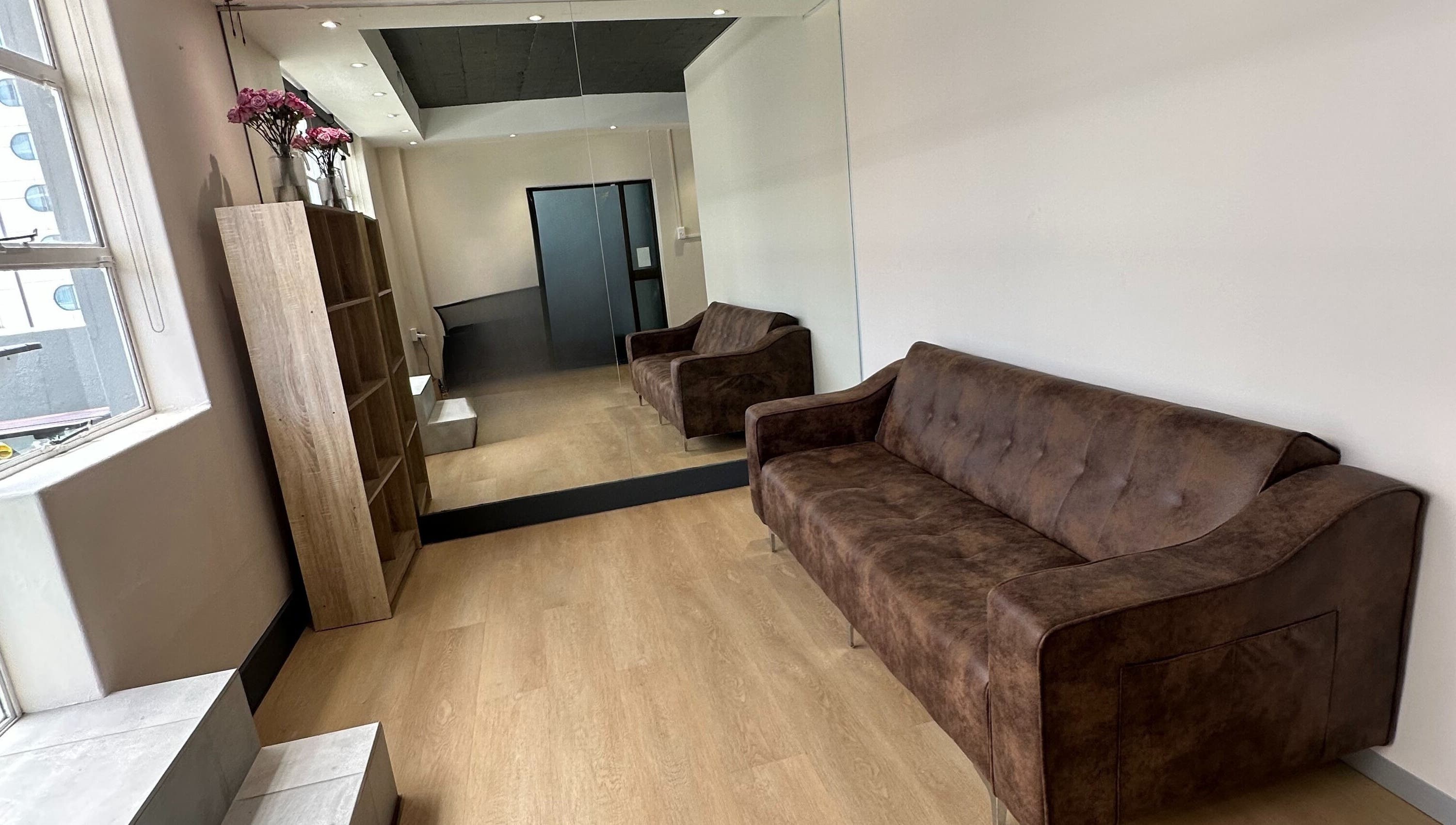 Interior of Wax On Wax Off in Sea Point, Western Cape, ZA with brown couches and a mirrored wall.
