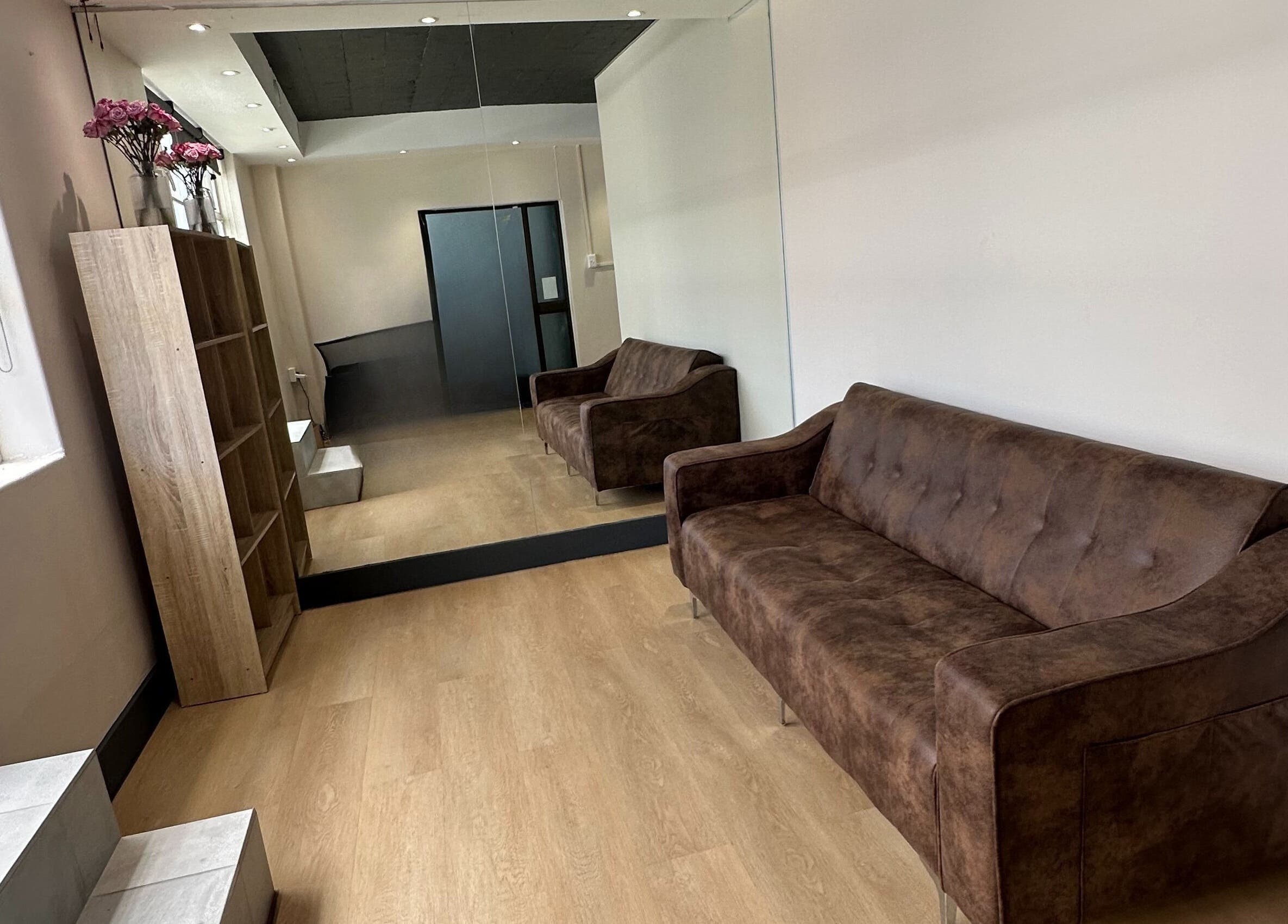 Interior of Wax On Wax Off in Sea Point, Western Cape, ZA with brown couches and a mirrored wall.