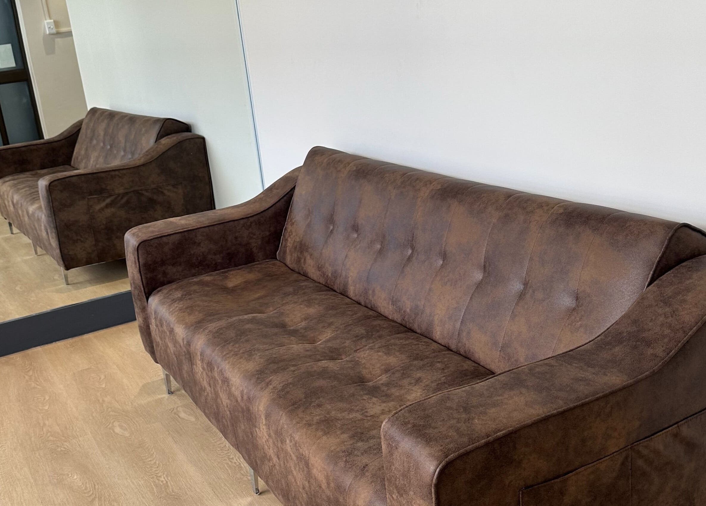 Cozy brown sofa at Wax On Wax Off in Sea Point, Western Cape, ZA, reflecting comfort in its mirrored setup.