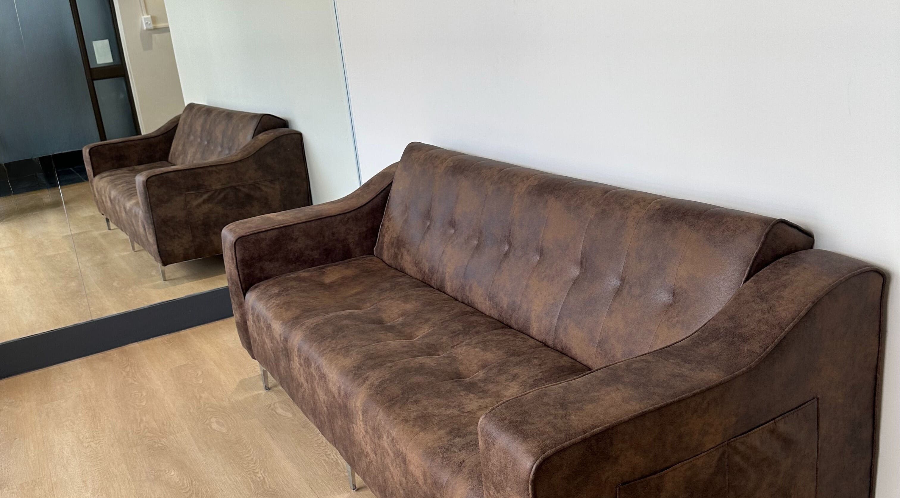 Cozy brown sofa at Wax On Wax Off in Sea Point, Western Cape, ZA, reflecting comfort in its mirrored setup.