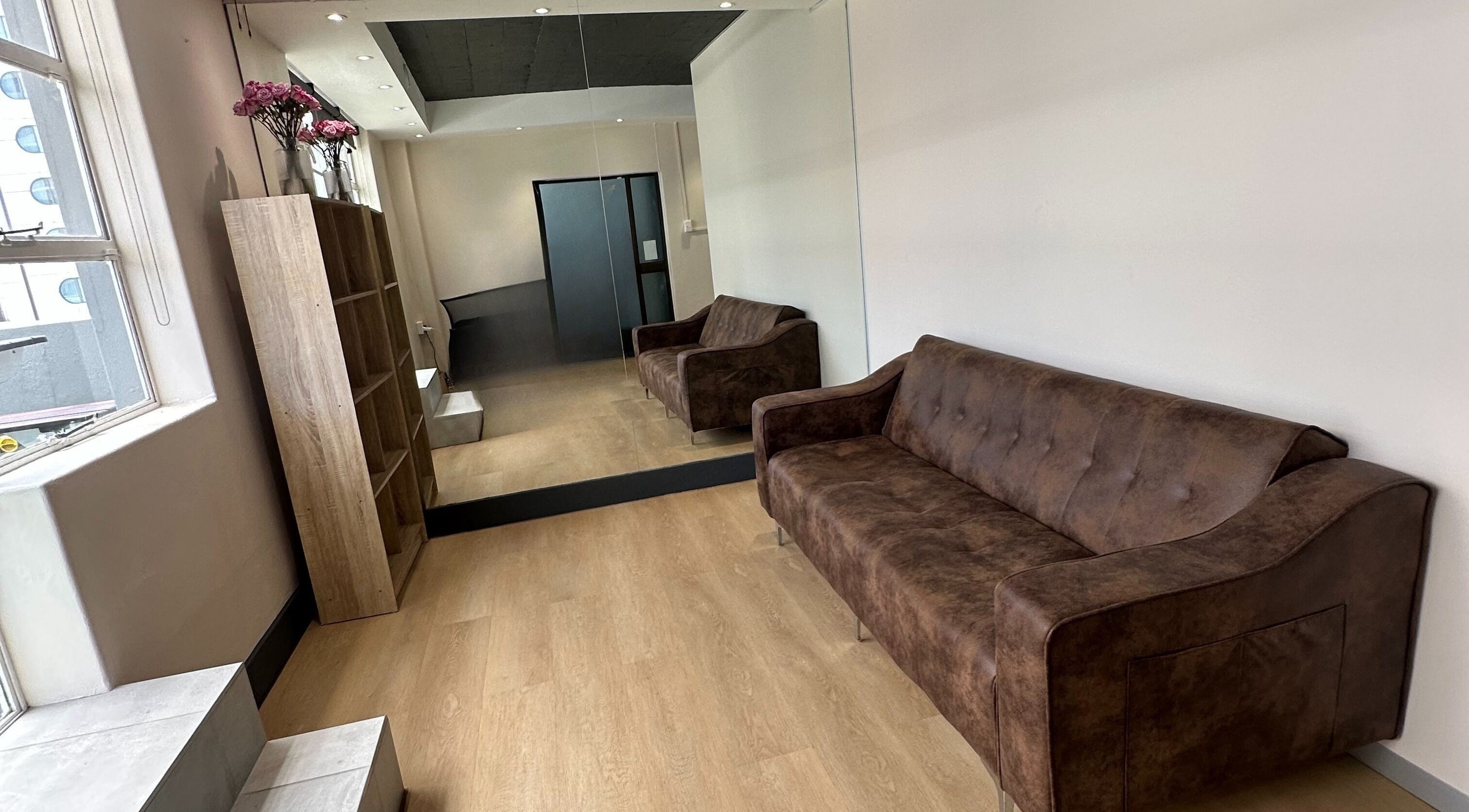 Cozy seating area at Wax On Wax Off, Cape Town, Western Cape, ZA, with brown sofa and mirrored wall.