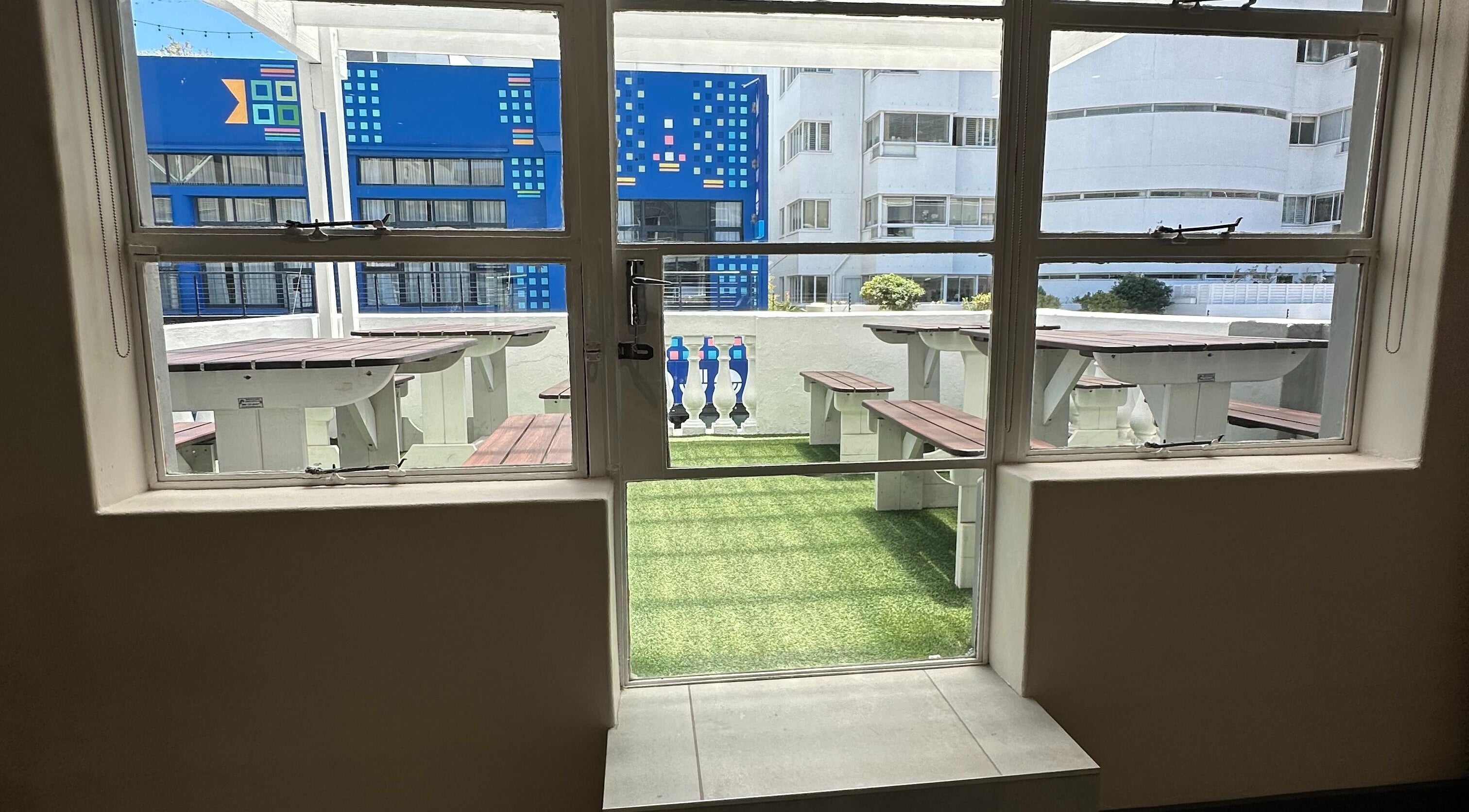 Relaxing rooftop area at Wax On Wax Off, Cape Town, Western Cape, ZA with tables and benches.