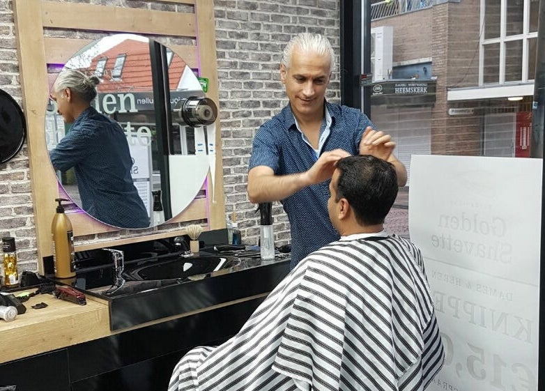 Kapster geeft hairstyling bij Golden Shavette, Uithoorn, Noord-Holland, NL.