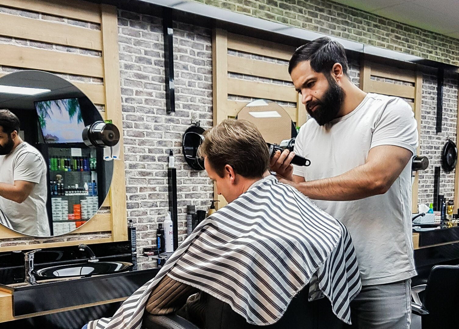 Barbier bij Golden Shavette in Uithoorn, Noord-Holland, NL geeft klant een trendy knipbeurt.