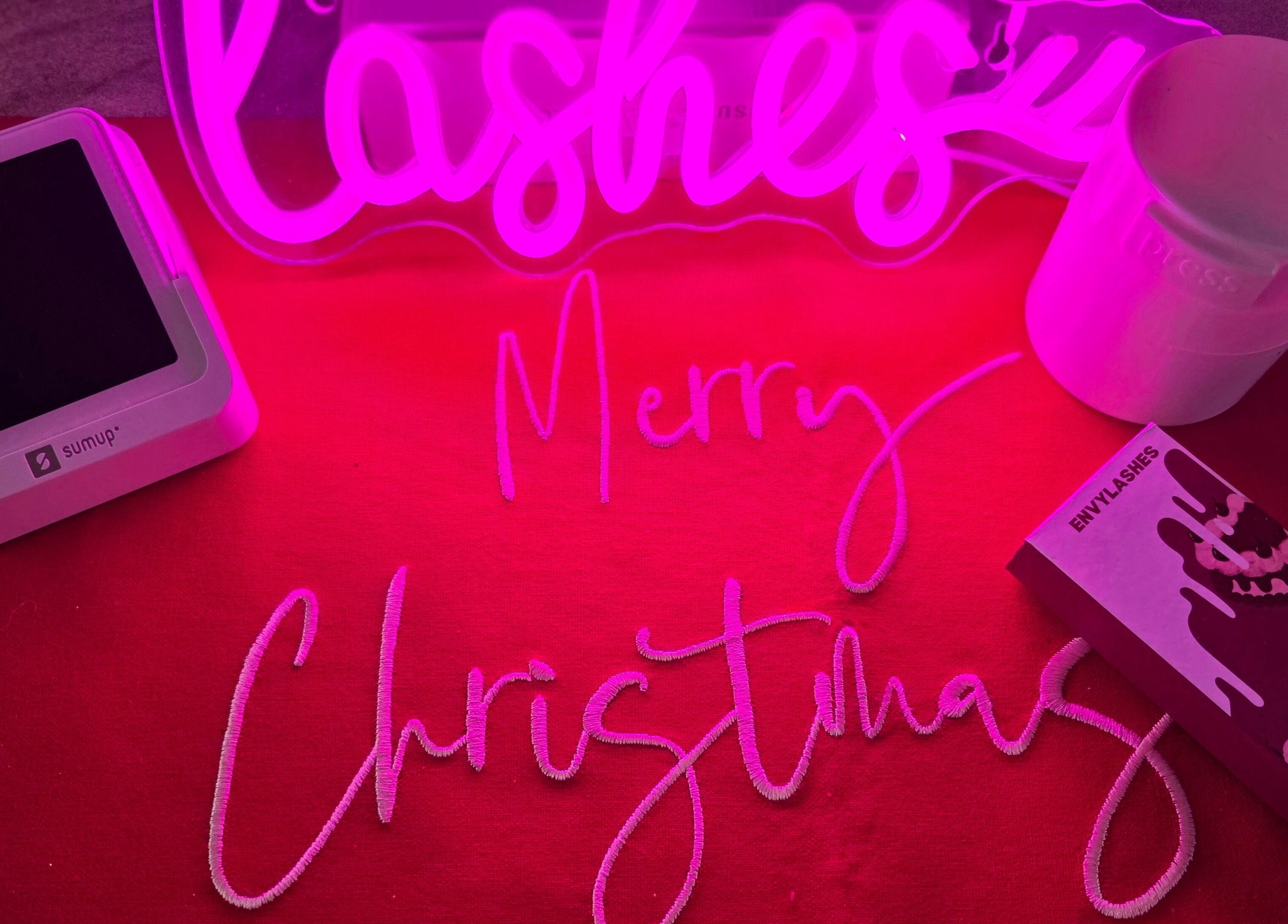 Pretty little beauty in Pembroke, Wales, GB, celebrates with festive decor and products under a pink glow.