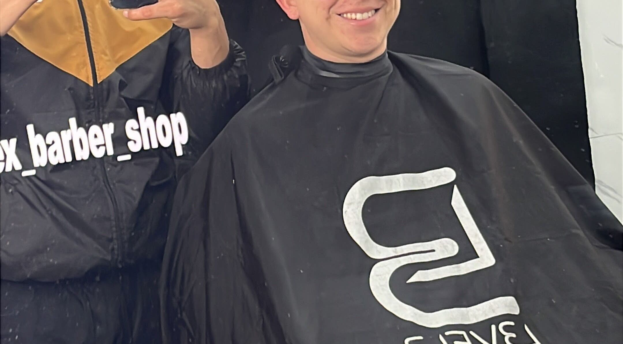 Cliente sonríe con satisfacción tras corte en J Alex Barber Shop, Peñalolén, Región Metropolitana, CL.