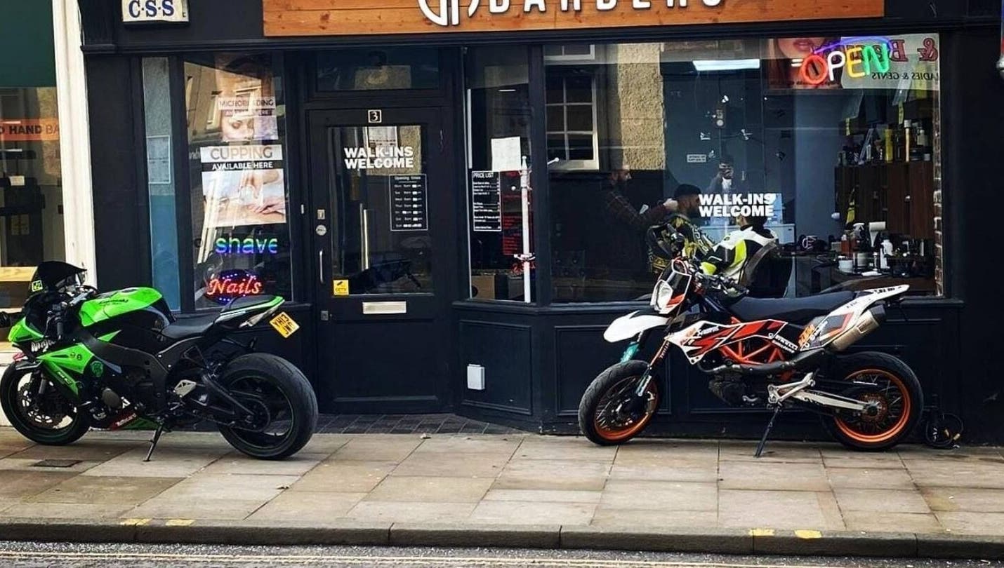 EH BARBERS Dalkeith, Scotland shopfront showcasing motorcycles outside its welcoming entrance.
