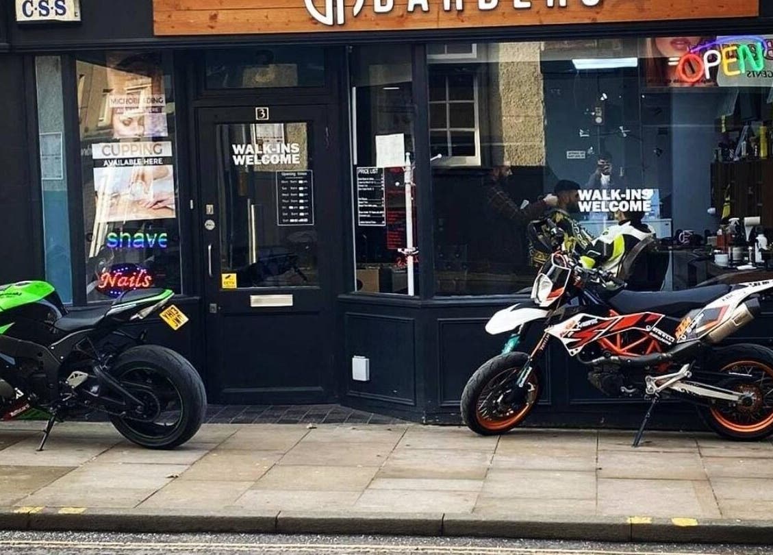 EH BARBERS Dalkeith, Scotland shopfront showcasing motorcycles outside its welcoming entrance.