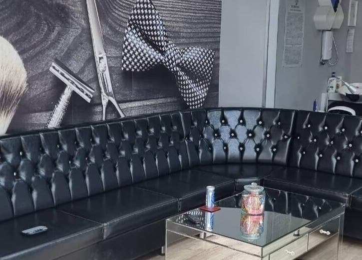 Stylish seating at EH BARBERS, Dalkeith, Scotland, GB with a modern black leather couch and wall decor.