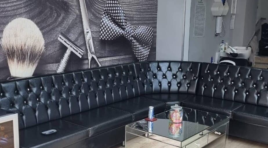 Stylish seating at EH BARBERS, Dalkeith, Scotland, GB with a modern black leather couch and wall decor.