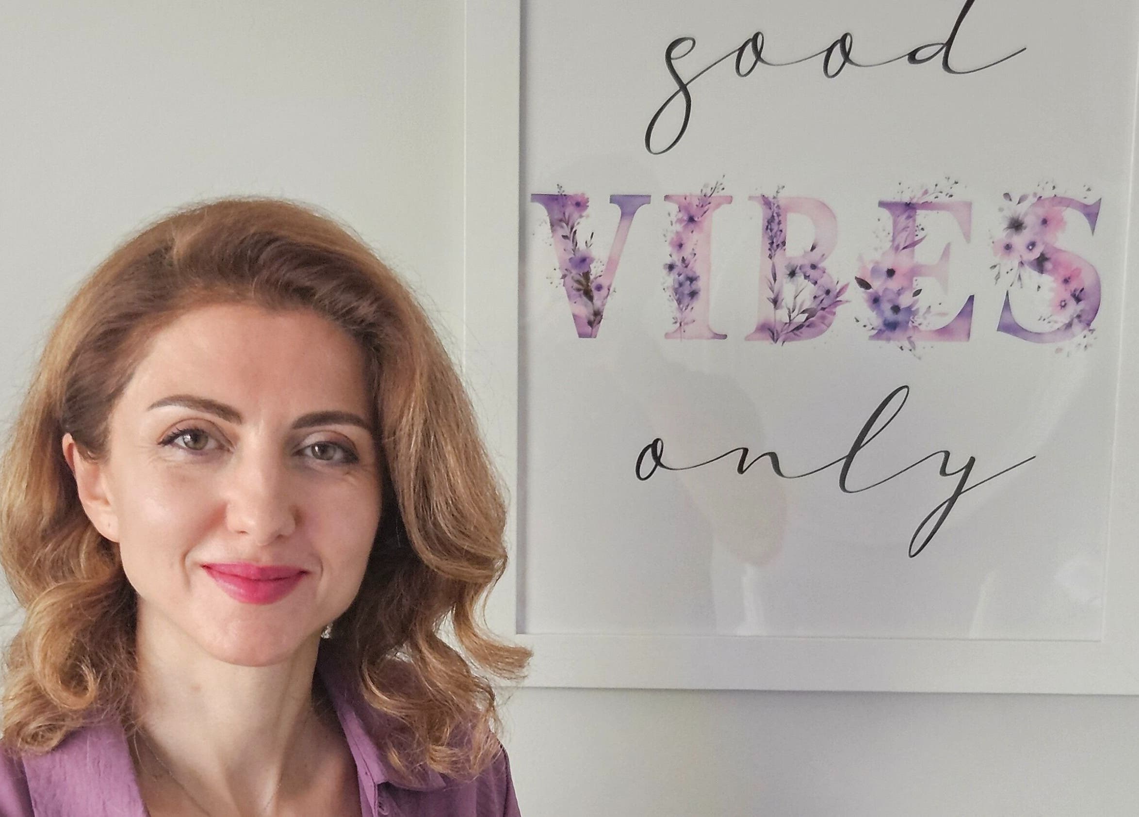 Owner of Harmonie KE - Kristine Hovhannisyan, Laval, Québec, CA, smiling beside 'Good Vibes Only' sign.