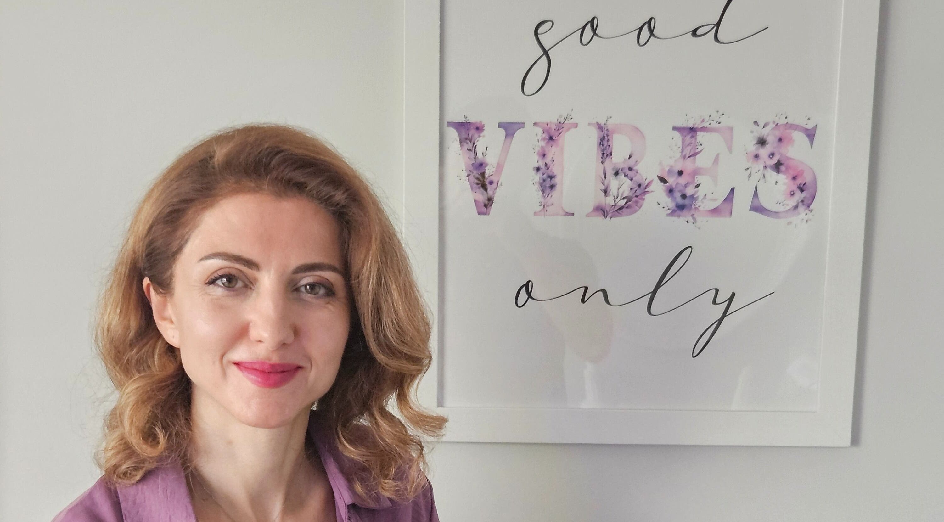 Owner of Harmonie KE - Kristine Hovhannisyan, Laval, Québec, CA, smiling beside 'Good Vibes Only' sign.