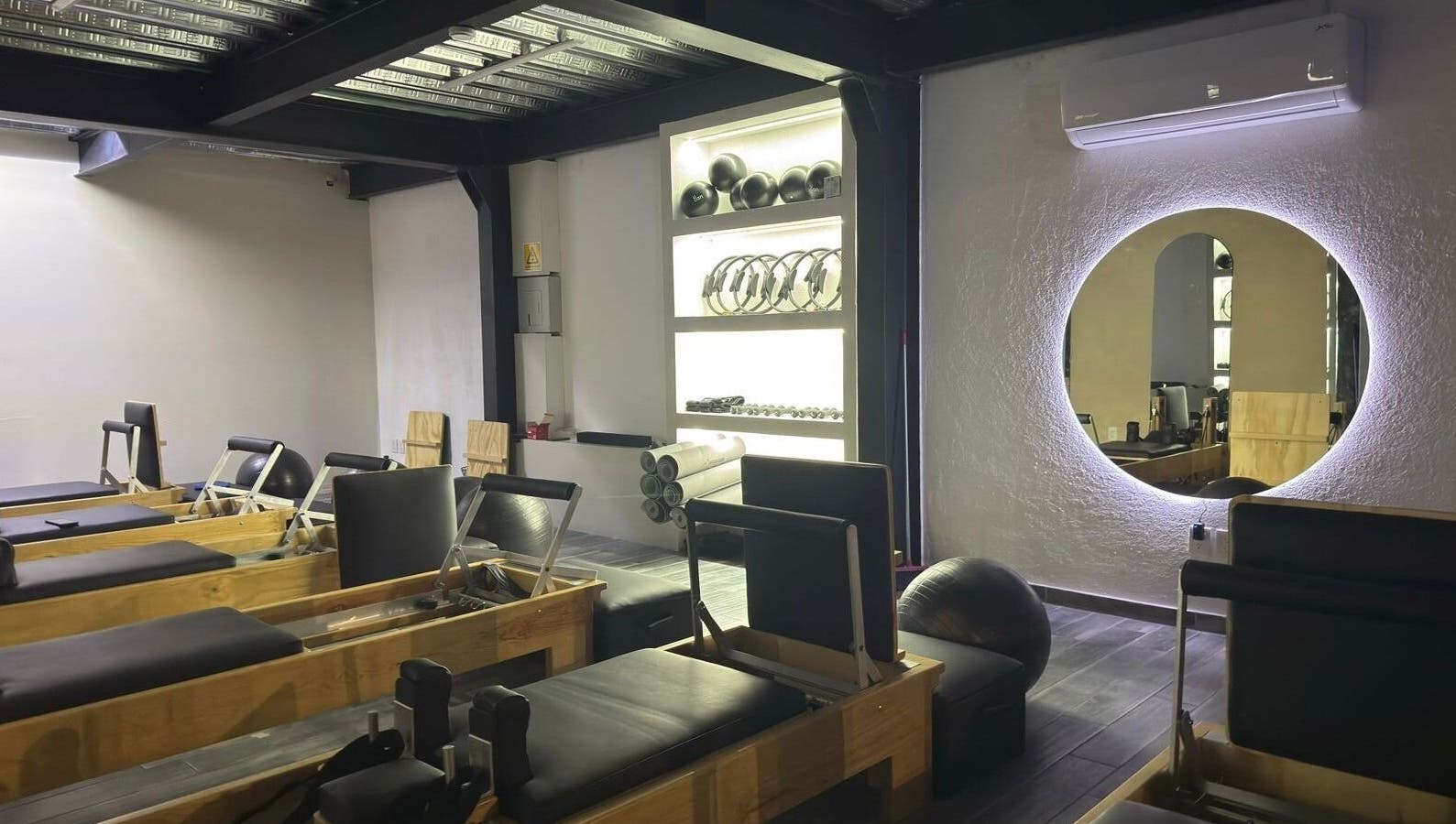 Interior moderno del Pilates Studio en Santiago De Querétaro, Querétaro, MX con equipos y espejo iluminado.
