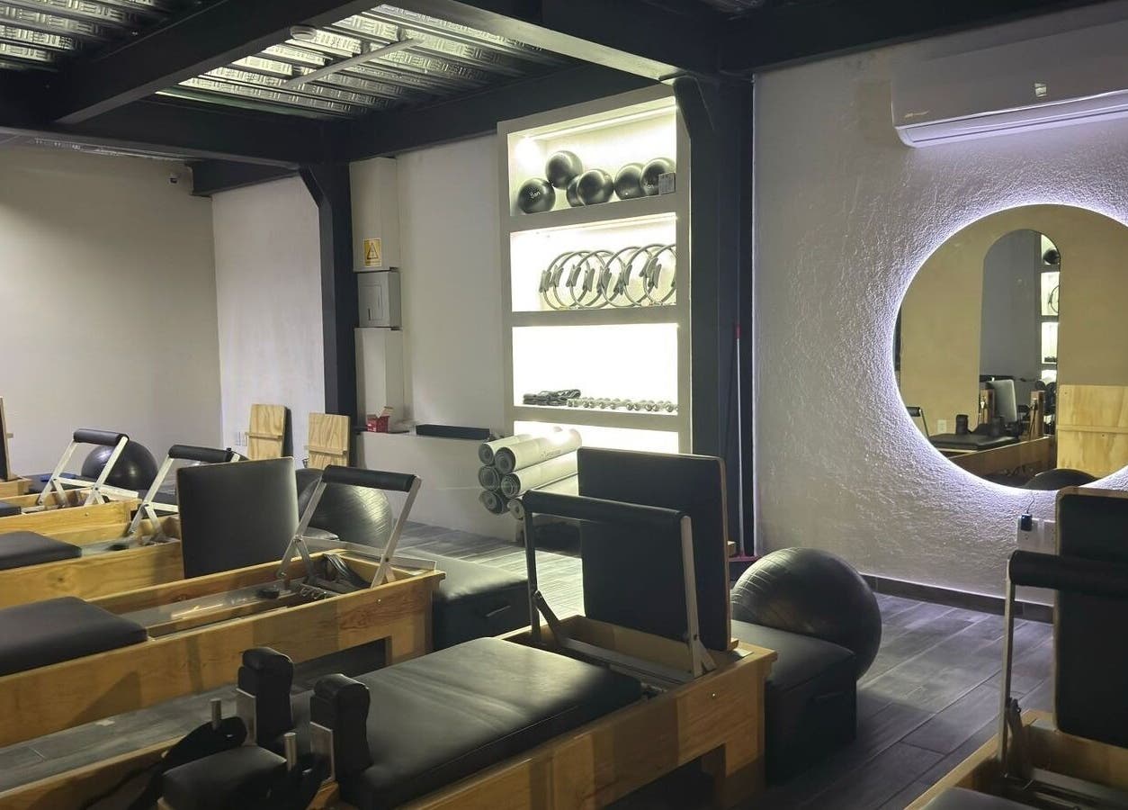 Interior moderno del Pilates Studio en Santiago De Querétaro, Querétaro, MX con equipos y espejo iluminado.