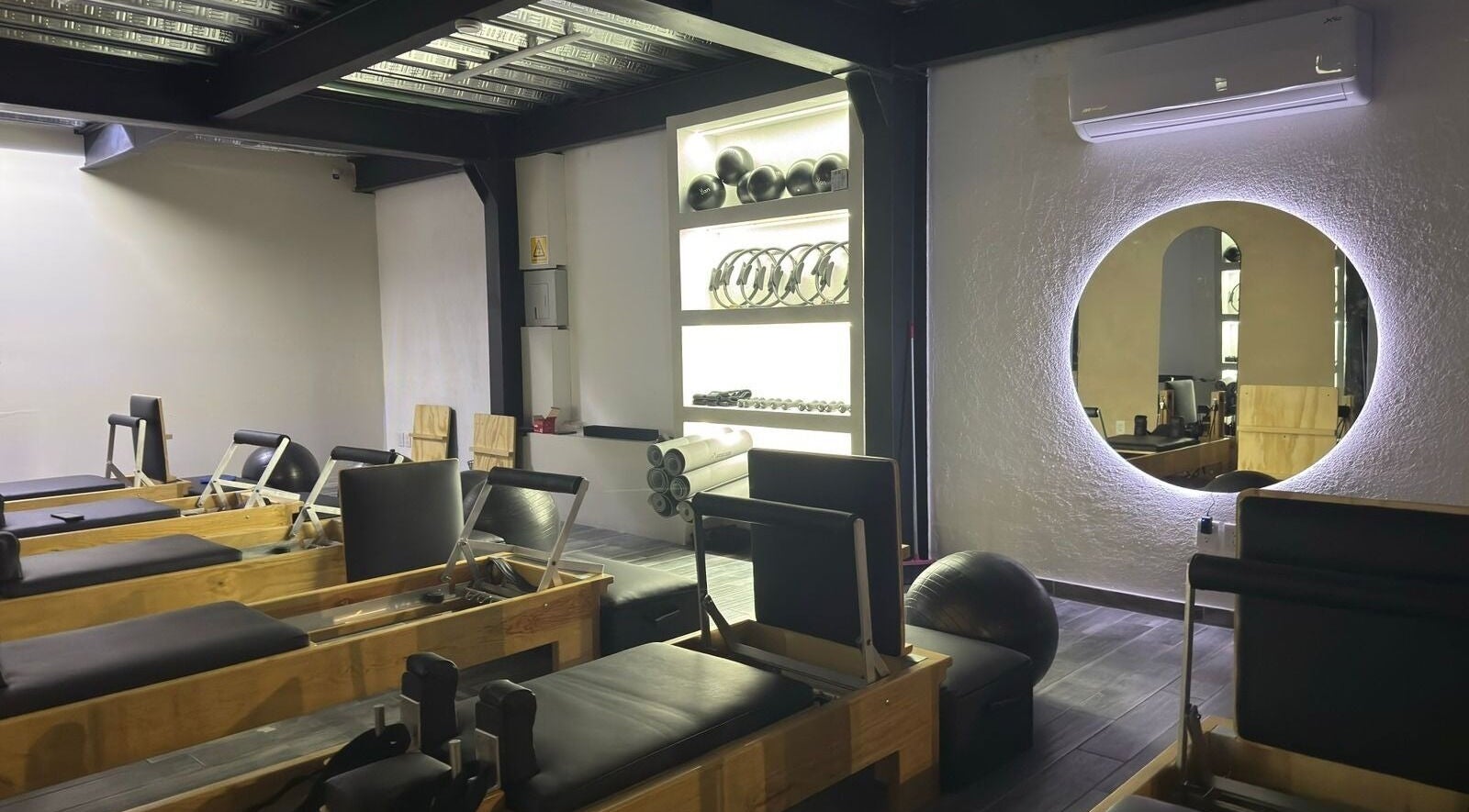 Interior moderno del Pilates Studio en Santiago De Querétaro, Querétaro, MX con equipos y espejo iluminado.