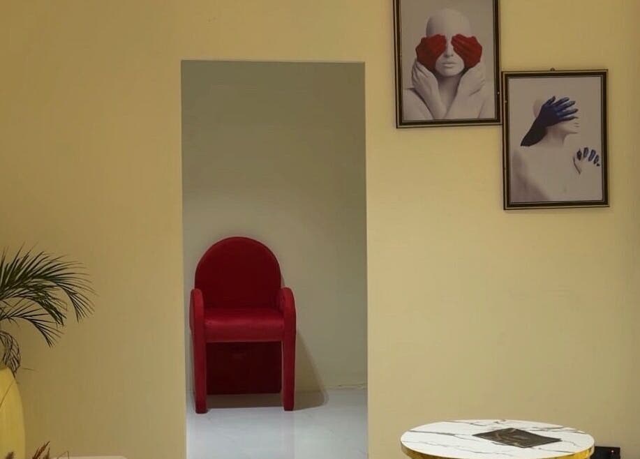 Cozy corner at Thewinkbeauty, Abuja, Federal Capital Territory, NG with red chair and art decor.