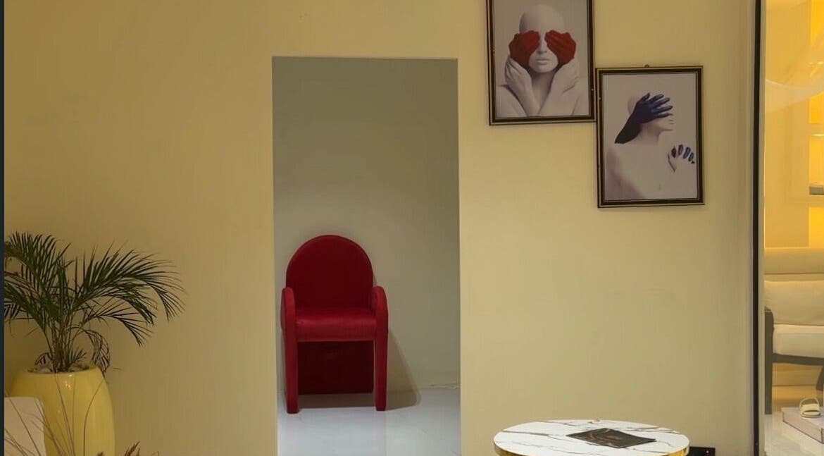Cozy corner at Thewinkbeauty, Abuja, Federal Capital Territory, NG with red chair and art decor.