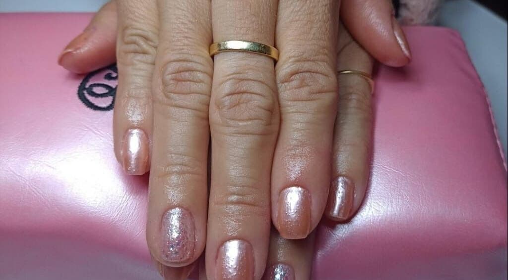 Unhas bem cuidadas e brilhantes no SLW Beauty, Baarn, Utrecht, NL, sobre almofada rosa.