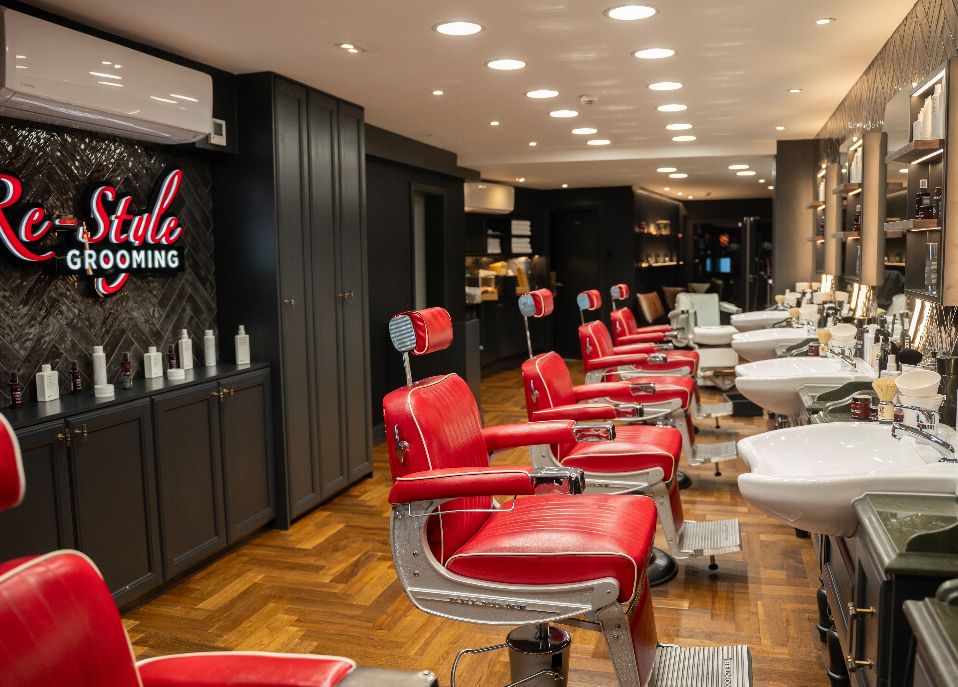 Modern interior of Re-Style Highgate salon in London, England, GB with red barber chairs and sleek decor.